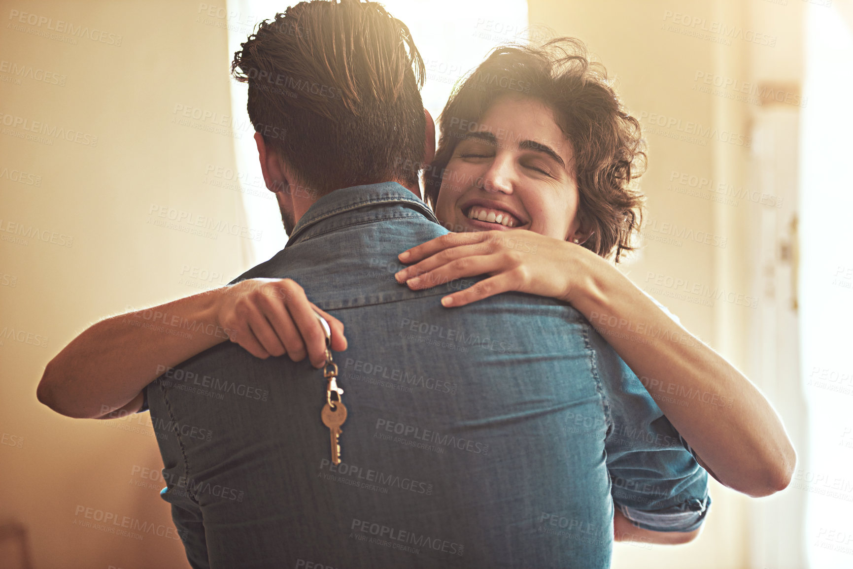 Buy stock photo Shot of a happy young couple hugging as they move into their new home