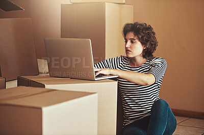 Buy stock photo Shot of a young woman sitting on the floor and using a laptop in her new home