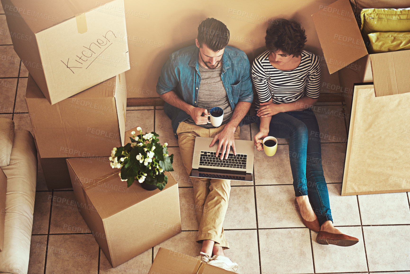 Buy stock photo Shot of a young couple relaxing on the floor and using a laptop in their new home