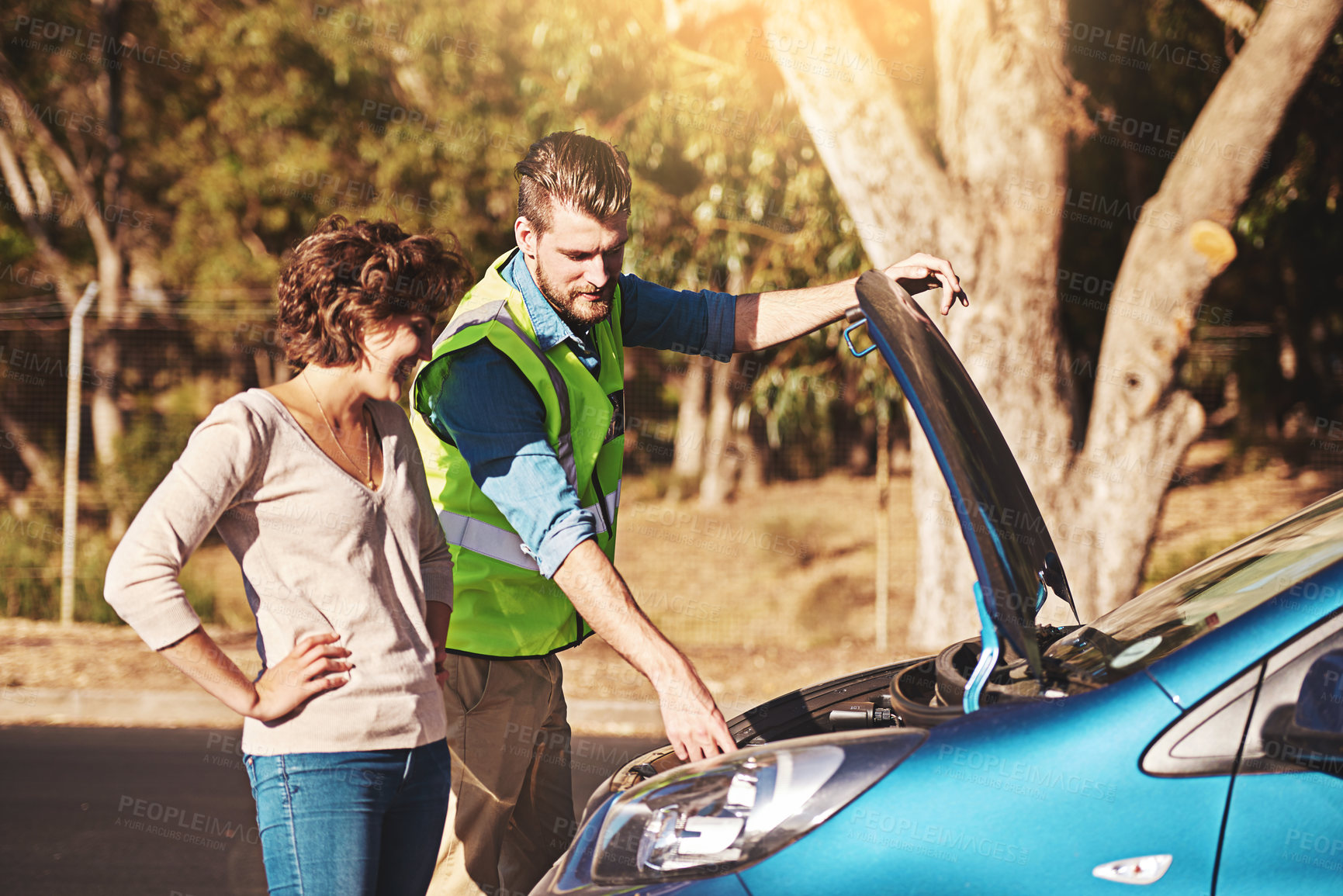 Buy stock photo Shot of a young woman receiving roadside assistance from a young man after breaking down