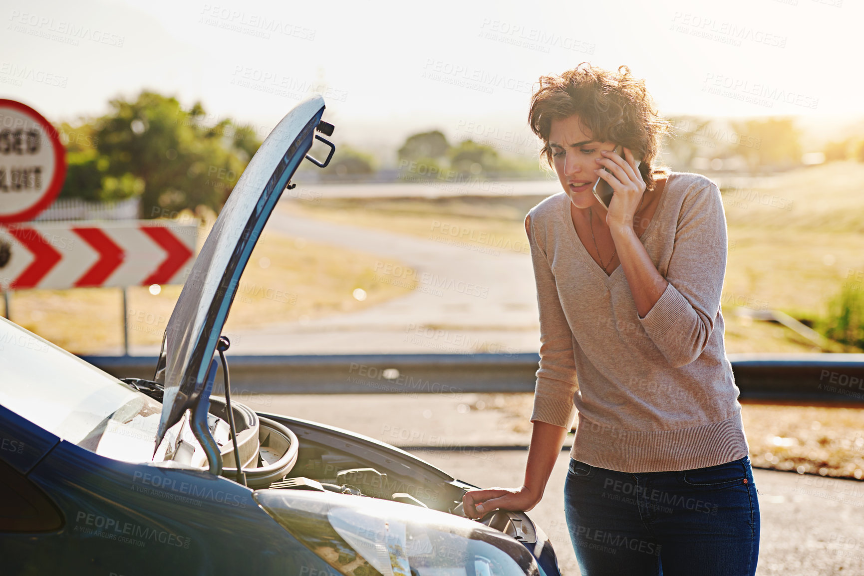 Buy stock photo Shot of a young woman calling roadside assistance after breaking down