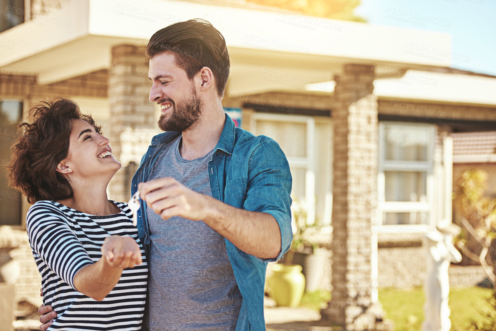 Buy stock photo Shot of a happy young couple holding the keys to their new home