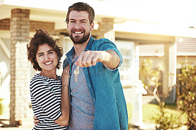 Buy stock photo Shot of a happy young couple holding the keys to their new home