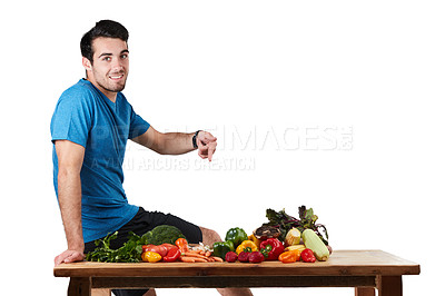 Buy stock photo Studio portrait of a handsome young man posing with a variety of fresh vegetables against a white background