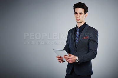 Buy stock photo Shot of a young businessman using a digital tablet against a grey background