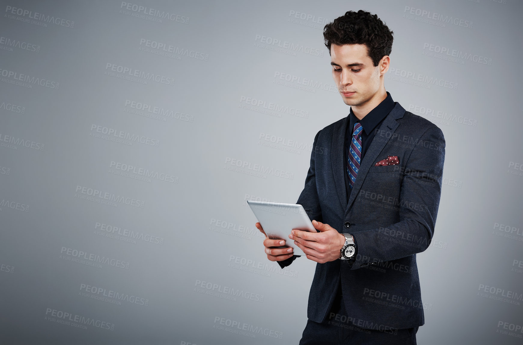 Buy stock photo Shot of a young businessman using a digital tablet against a grey background