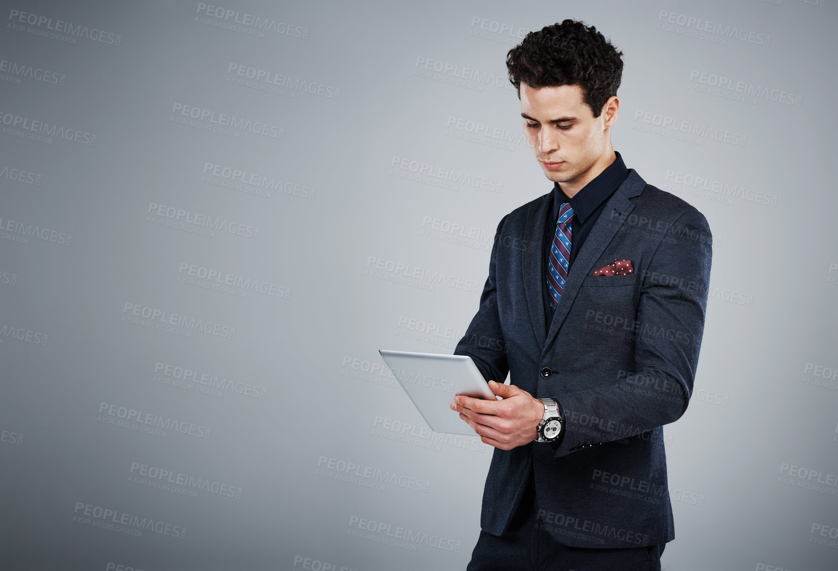 Buy stock photo Shot of a young businessman using a digital tablet against a grey background
