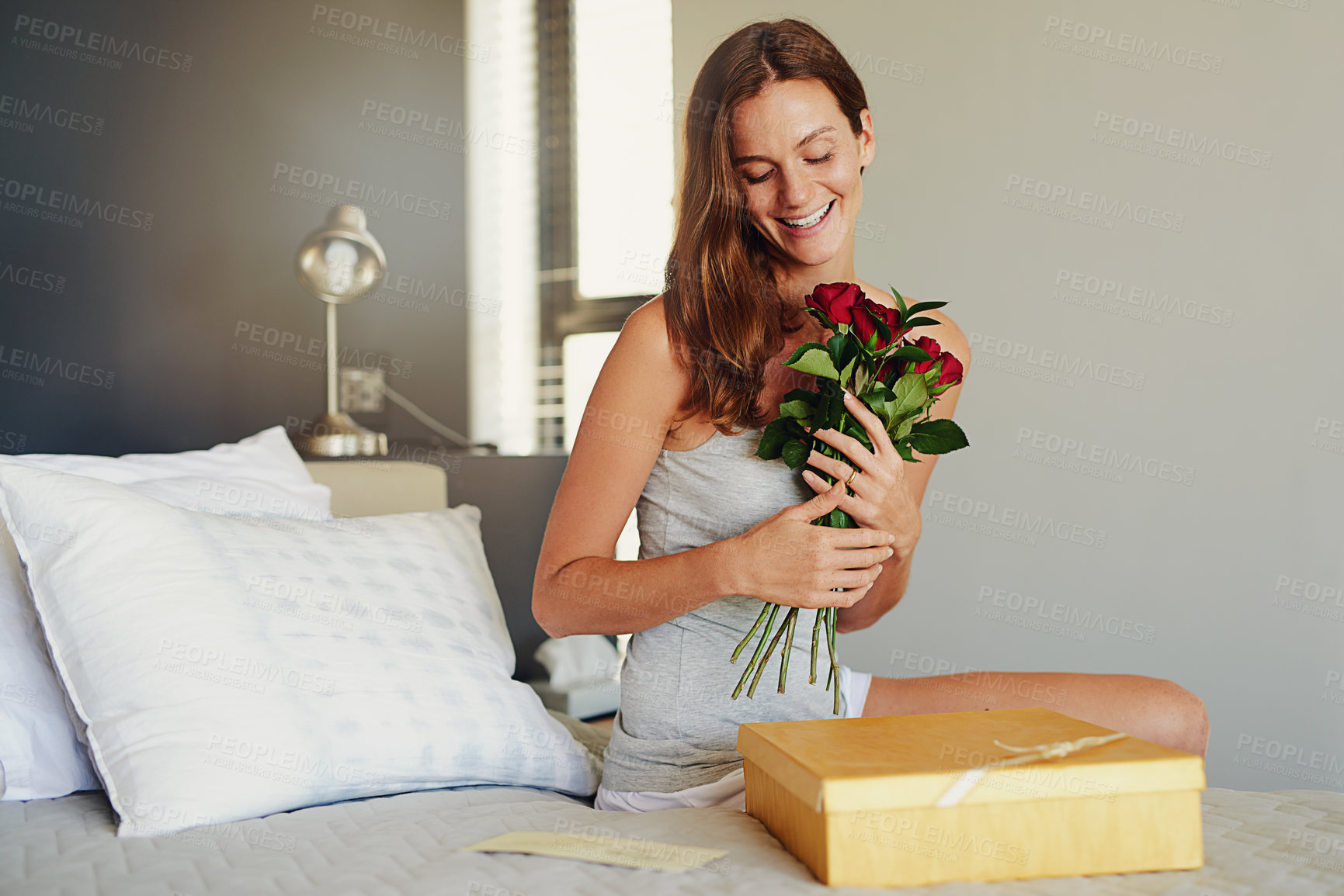 Buy stock photo Woman, bed and excited for roses, present or happy in house on birthday, valentines day or celebration. Girl, hug flowers or bouquet by cardboard package, gift or smile on bedroom, thinking and home