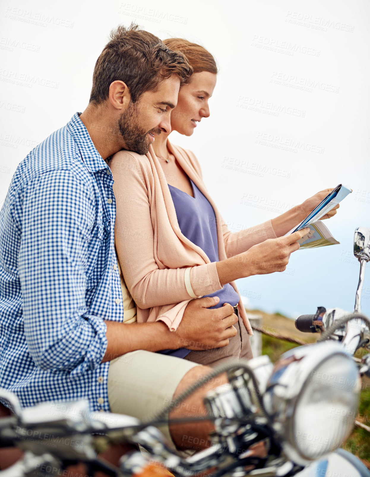 Buy stock photo Shot of an affectionate couple looking at a map while out on their motorcycle