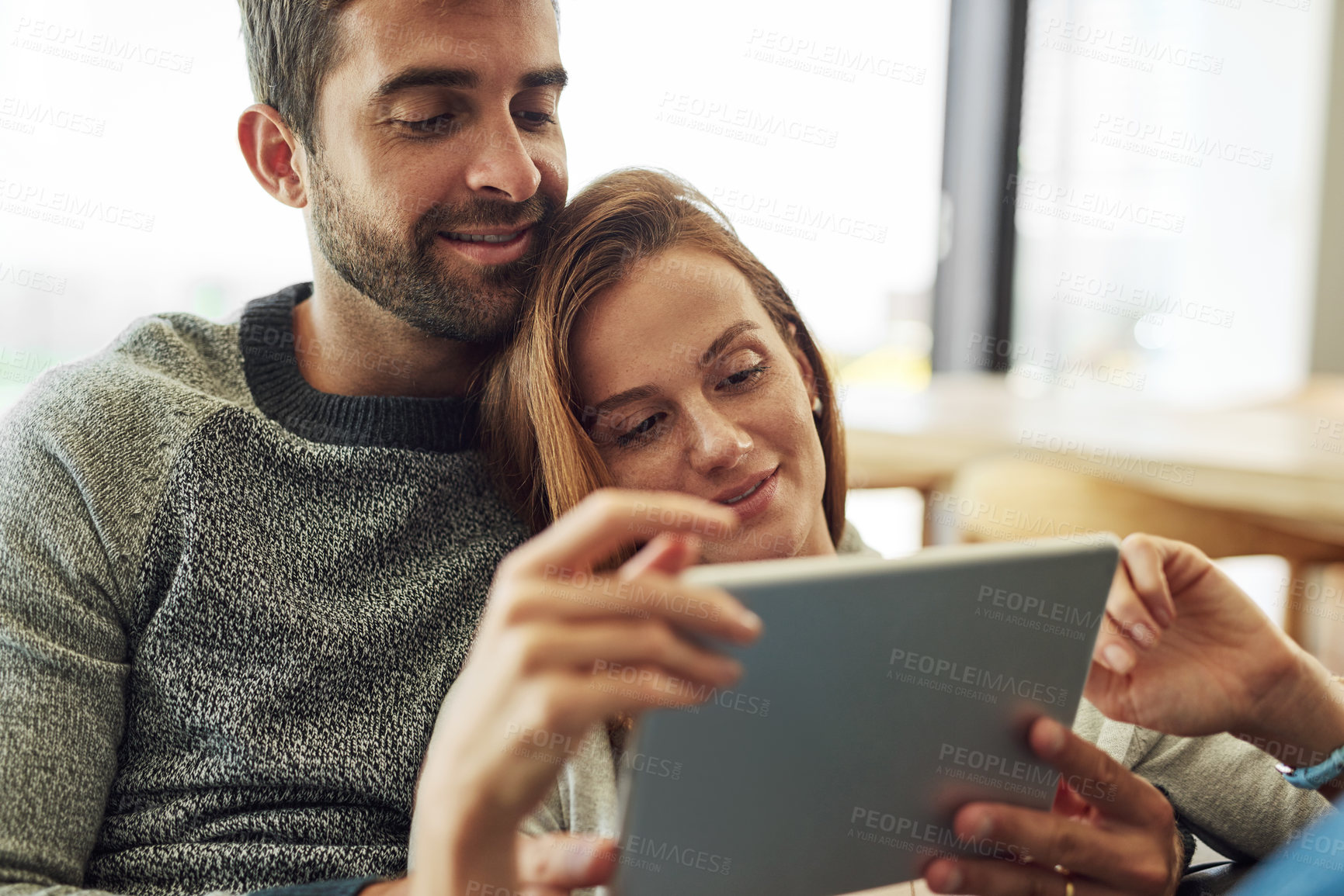 Buy stock photo High angle shot of an affectionate young couple using a tablet while relaxing on their sofa at home