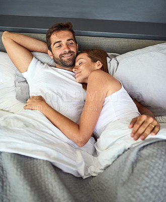 Buy stock photo Shot of a happy young couple relaxing in bed together at home