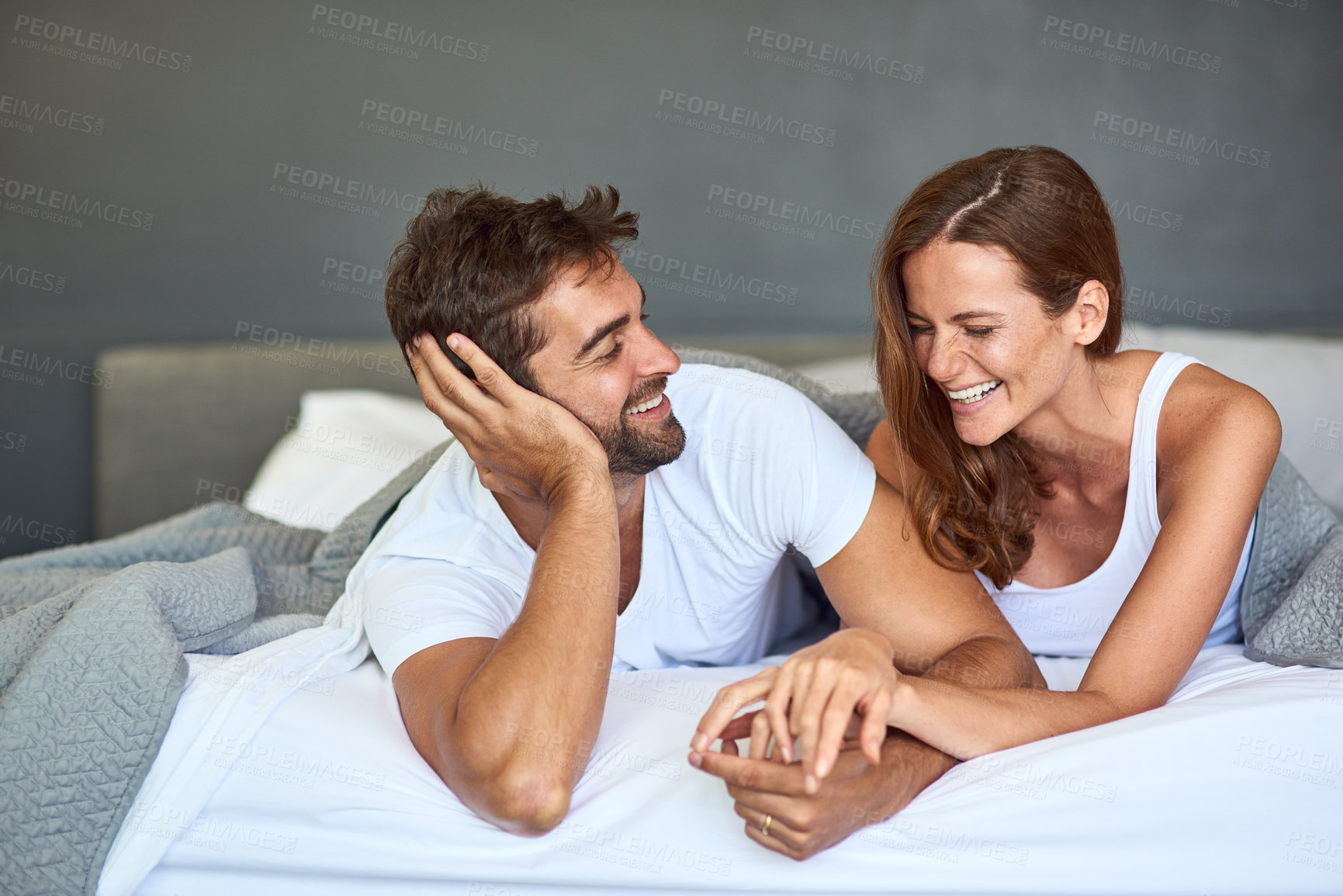 Buy stock photo Happy couple, wake up and laughing in bedroom, morning or support for marriage commitment at house. Love, bonding or funny people with smile for romantic relationship, joke or anniversary together