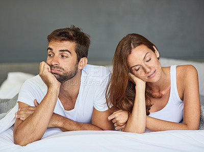 Buy stock photo Shot of a young couple ignoring each other in the bedroom