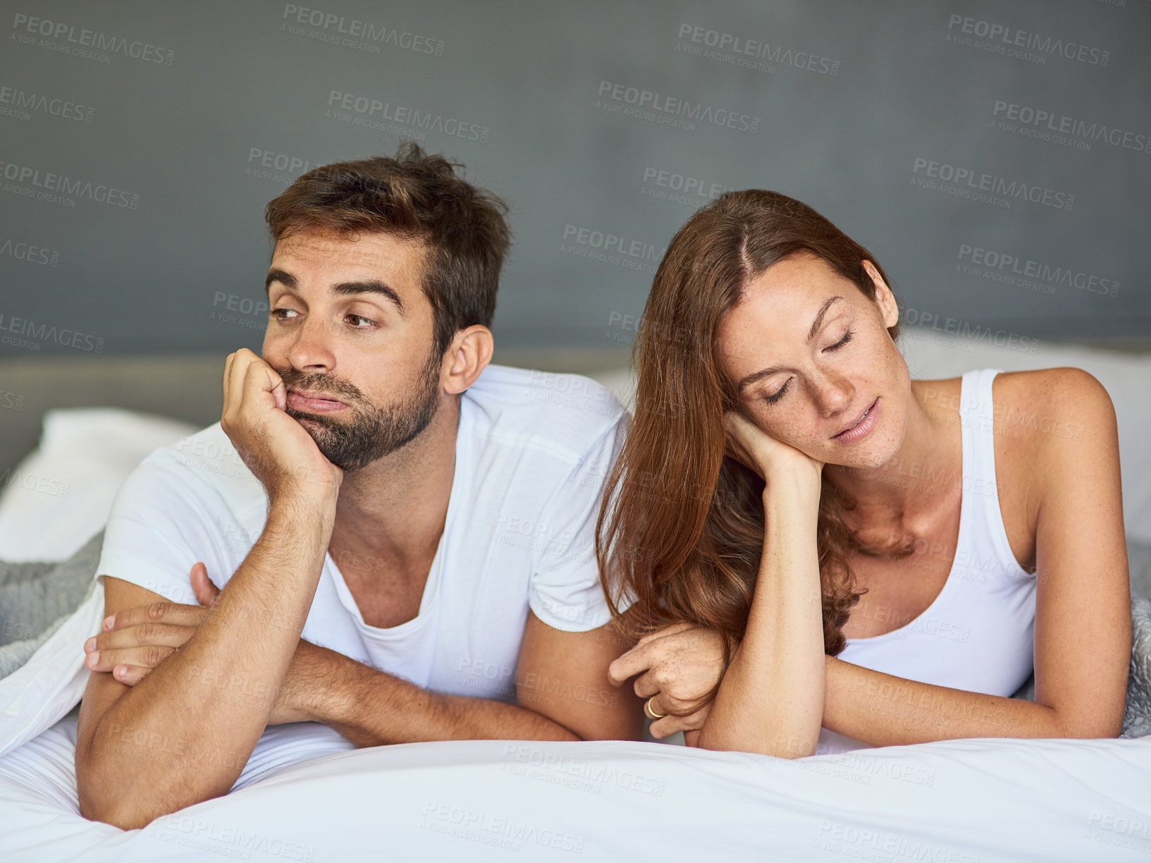 Buy stock photo Shot of a young couple ignoring each other in the bedroom