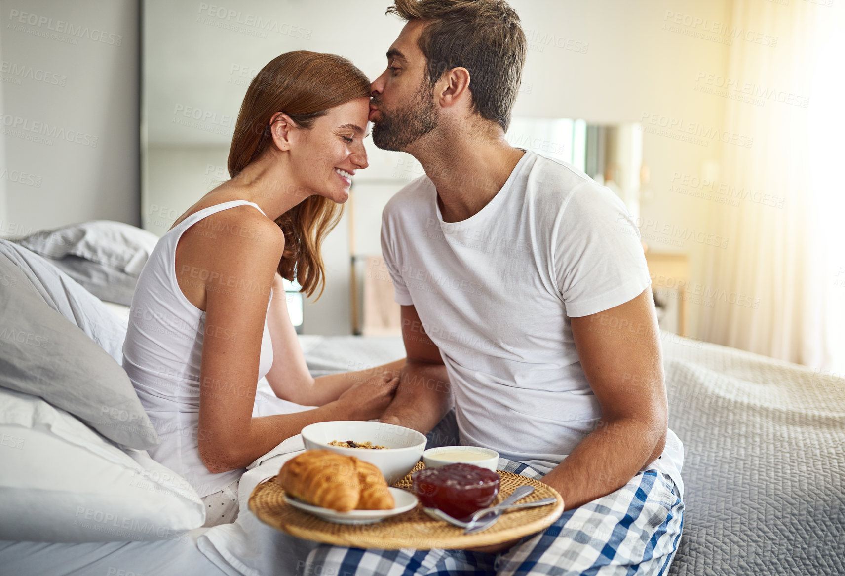 Buy stock photo Couple, kiss and happy in bed for breakfast at hotel with room service for love and valentines day. Man, woman and, smile in morning in bedroom for support, food and celebration together on vacation