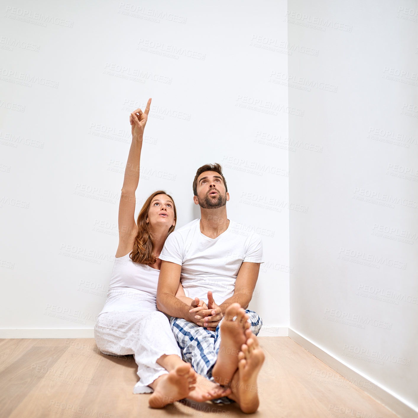 Buy stock photo Couple, floor and pointing up in home for moving, interior design or relax by mockup space. Man, woman and decoration of dream house, remodeling and planning renovation of property on wall together