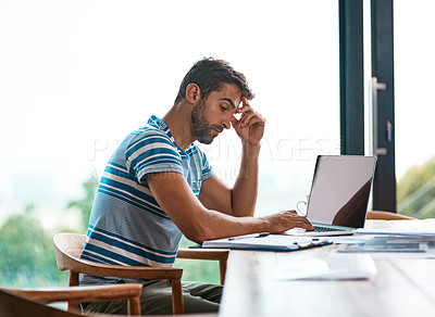 Buy stock photo Cropped shot of a handsome young male entrepreneur looking thoughtful while working from his home office