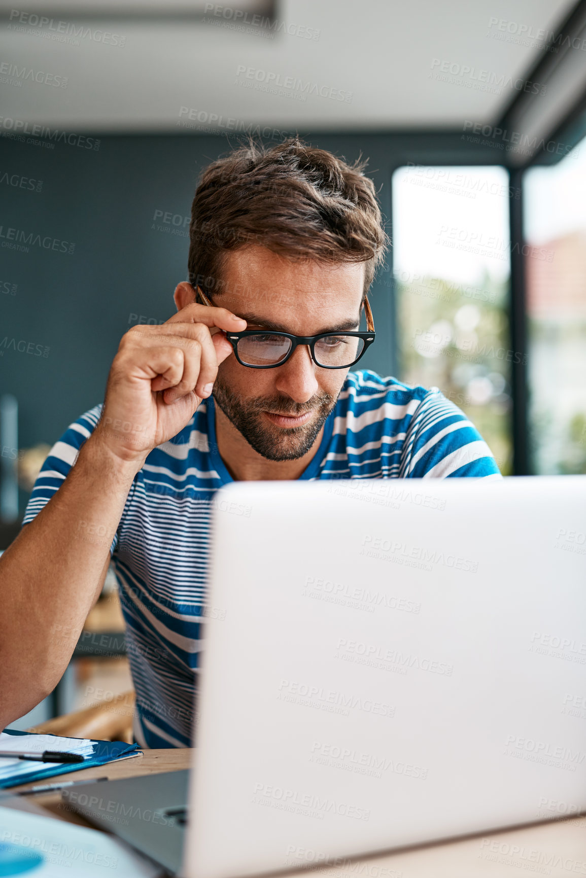 Buy stock photo Cropped shot of a handsome young male entrepreneur working from his home office