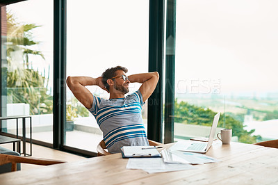 Buy stock photo Cropped shot of a handsome young male entrepreneur sitting with his hands behind his head while working from his home office