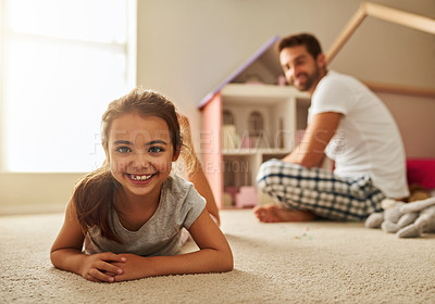Buy stock photo Portrait of an adorable young girl lying on her bedroom floor with her father in the background