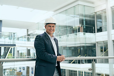 Buy stock photo Portrait of a cheerful professional male architect standing next to a development site while looking at the camera inside of a building