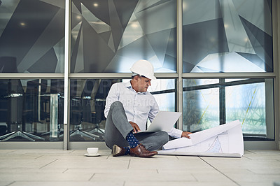 Buy stock photo Shot of a focused professional male architect sitting on the floor outside while working on a laptop