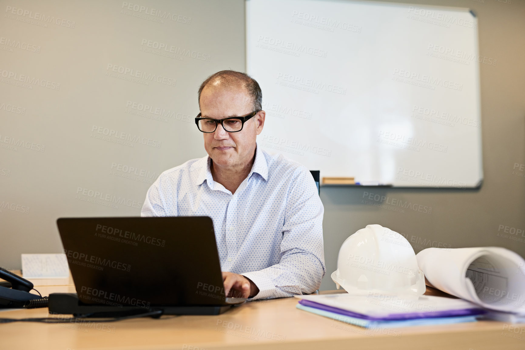 Buy stock photo Shot of a focused professional businessman working on his laptop while being seated in a office