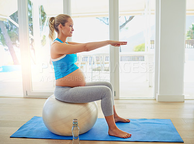 Buy stock photo Shot of a pregnant woman working out with an exercise ball at home