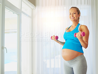 Buy stock photo Shot of a pregnant woman working out with weights at home