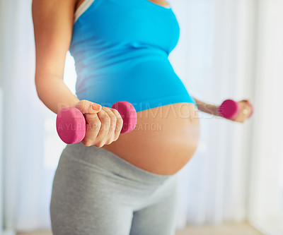 Buy stock photo Cropped shot of a pregnant woman working out with weights at home
