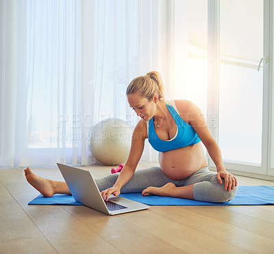 Buy stock photo Shot of a pregnant woman using a laptop during a workout at home