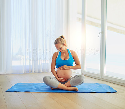 Buy stock photo Shot of a pregnant woman working out on an exercise mat at home