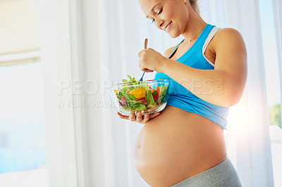 Buy stock photo Shot of a fit pregnant woman eating a bowl of salad at home