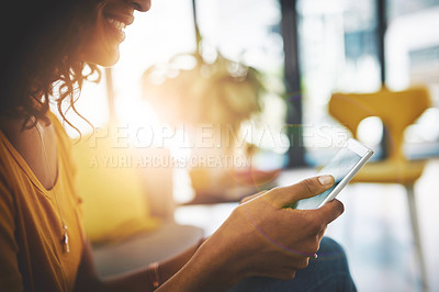 Buy stock photo Cropped shot of an unrecognizable young woman using her cellphone while relaxing at home on the weekend