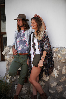 Buy stock photo Shot of a trendy young couple standing together against the wall of a building outside