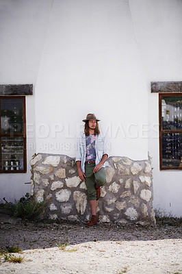 Buy stock photo Shot of a trendy young man leaning against the wall of a building outside