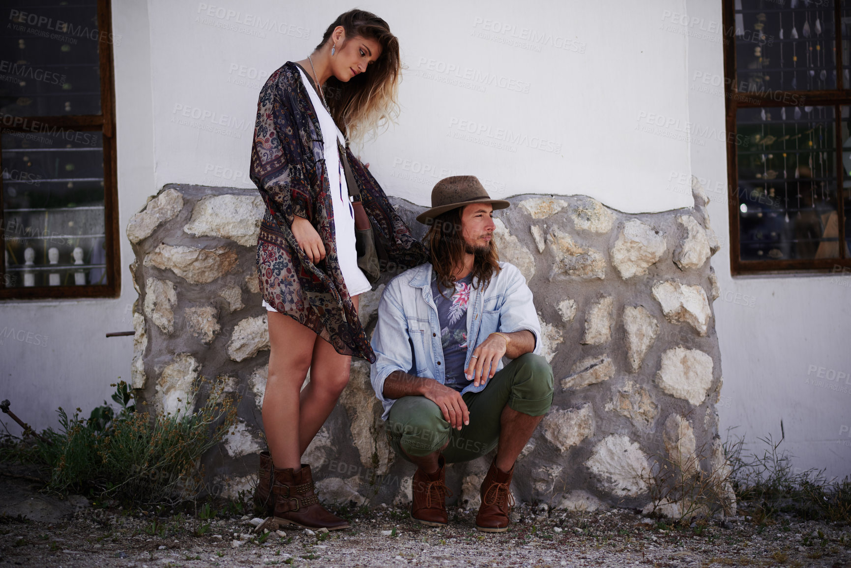 Buy stock photo Shot of a trendy young couple standing together against the wall of a building outside