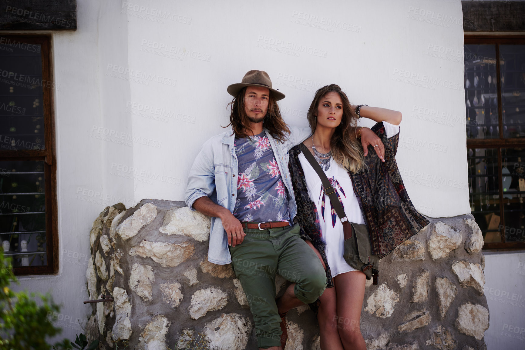 Buy stock photo Shot of a trendy young couple standing together against the wall of a building outside