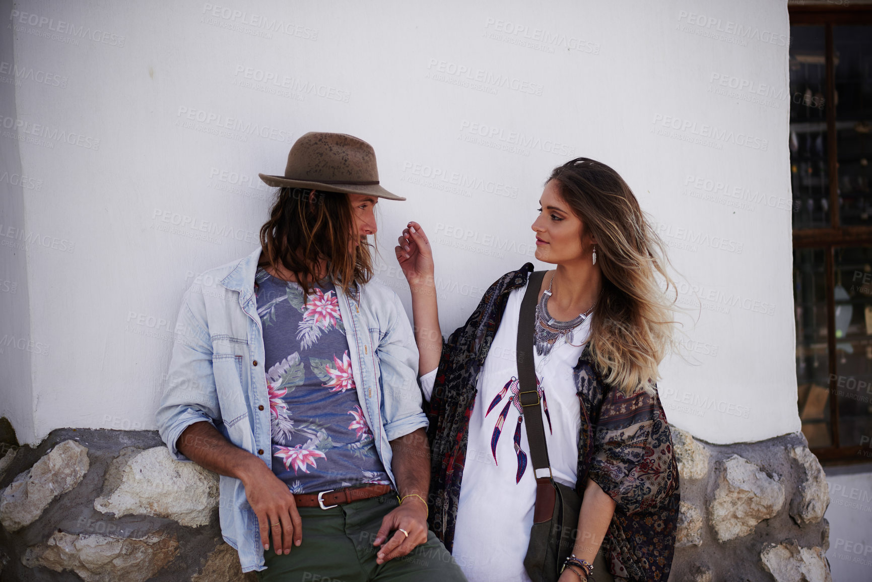 Buy stock photo Shot of a trendy young couple standing together against the wall of a building outside