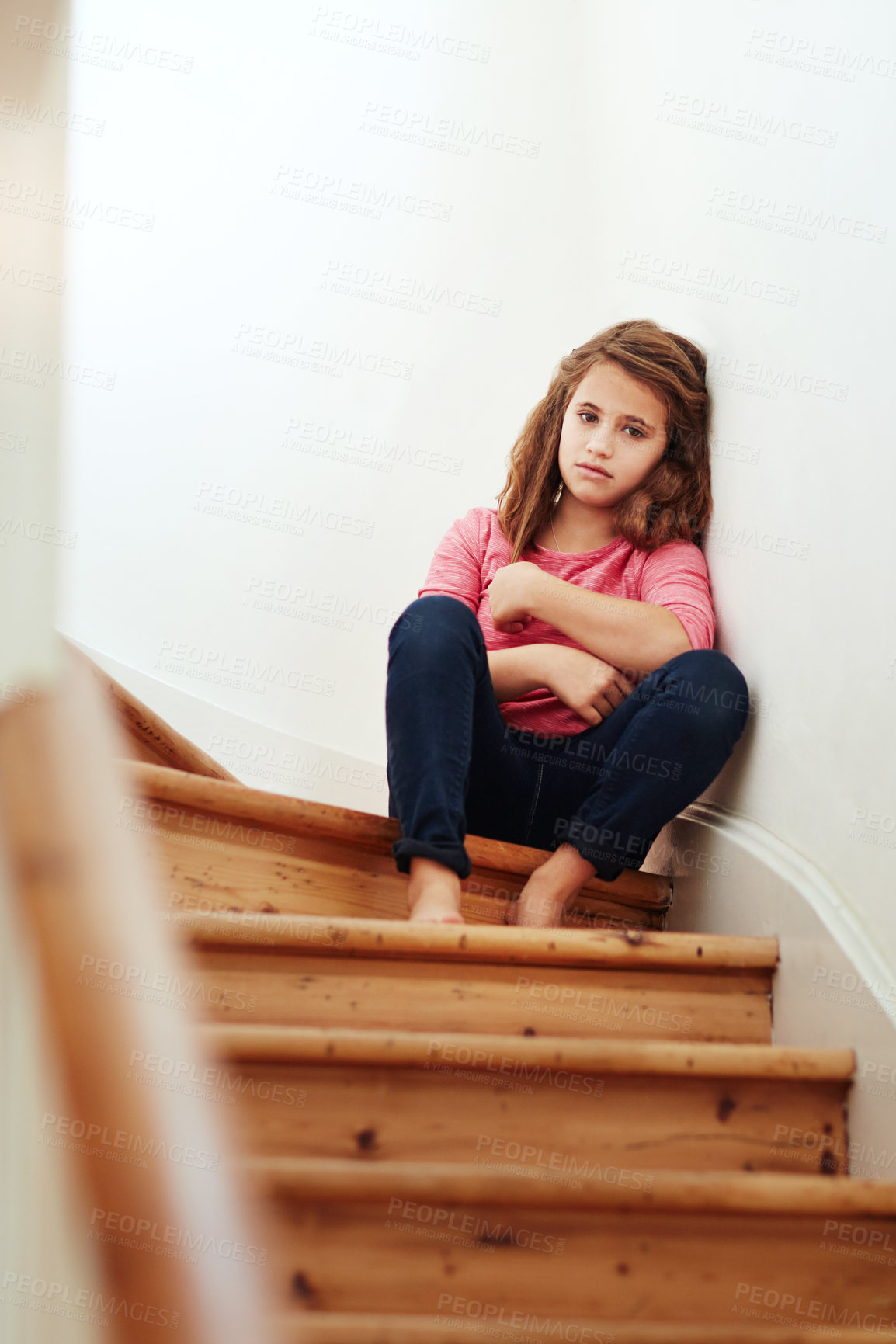 Buy stock photo Shot of a little girl looking sad while sitting on the stairs at home