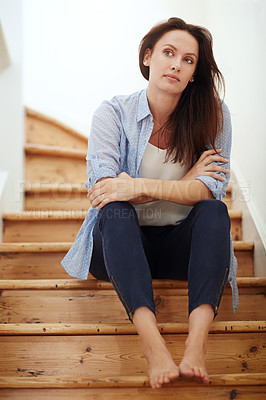 Buy stock photo Shot of a young woman sitting on the staircase at home