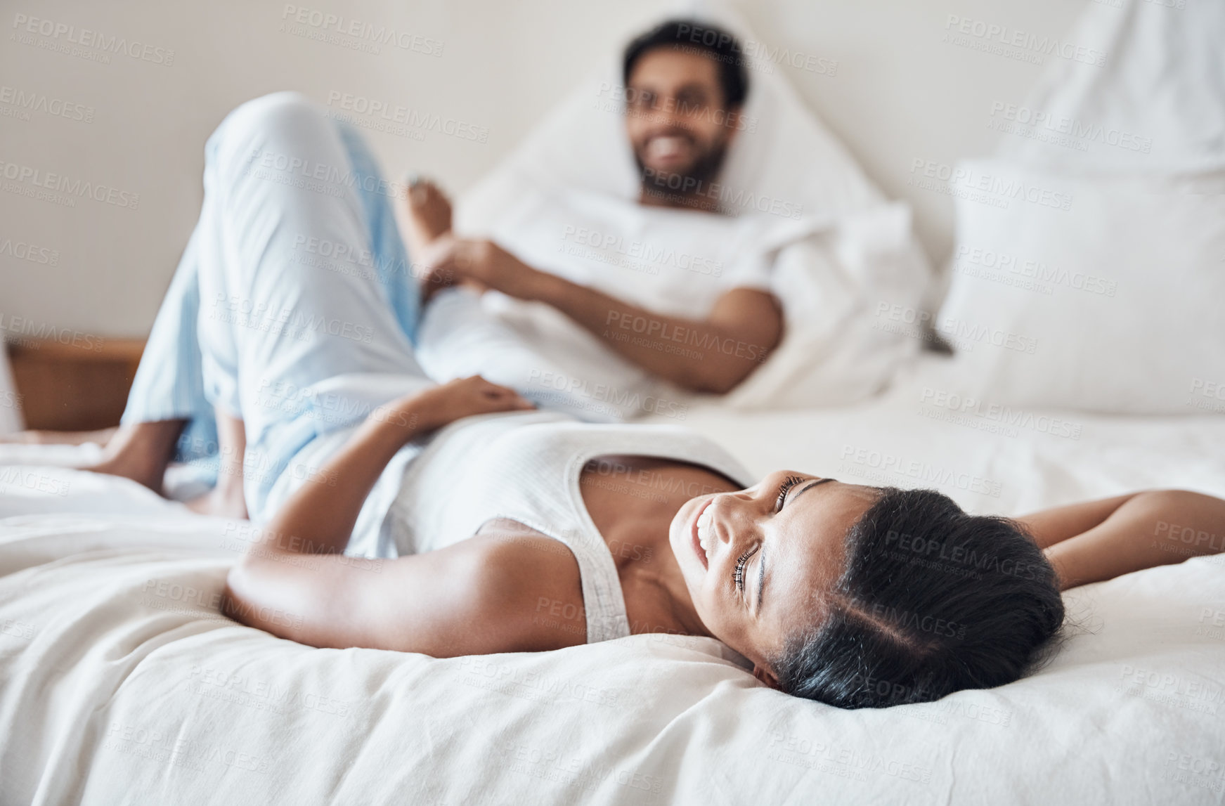 Buy stock photo Shot of a young couple lying on a bed together at home