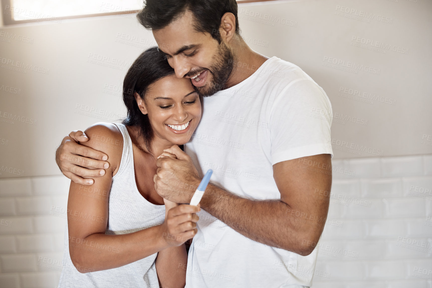 Buy stock photo Hug, man and woman in bathroom with pregnancy test, smile and family planning in home. Good news, surprise results and pregnant couple embrace in celebration of health, wellness and happy in marriage