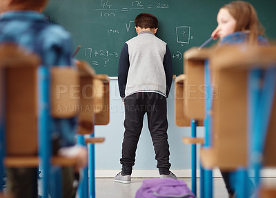 Buy stock photo Rear view shot of an elementary school boy leaning with his head on the chalkboard in class