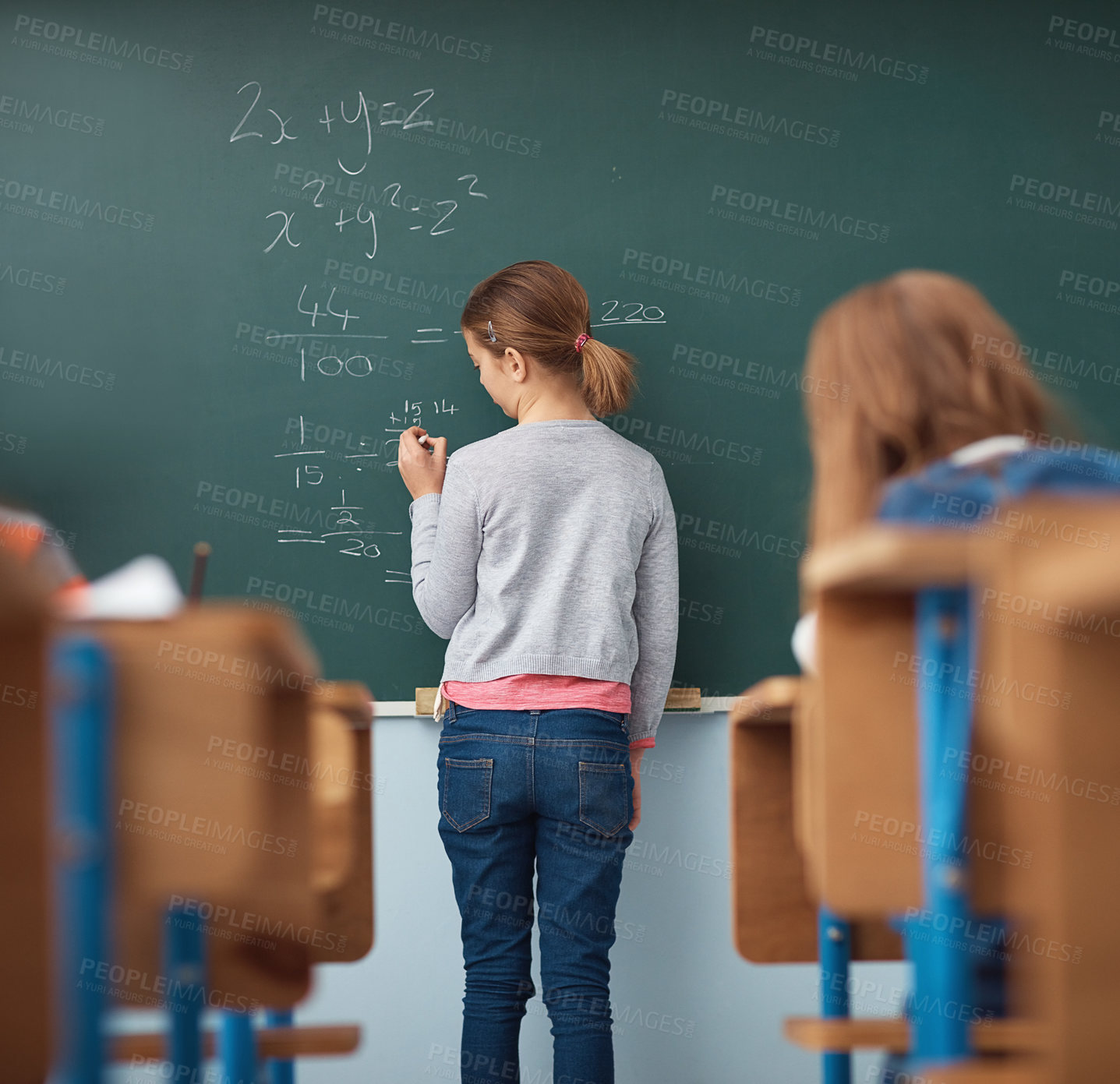 Buy stock photo Rear view shot of an elementary school girl writing on the chalkboard in class