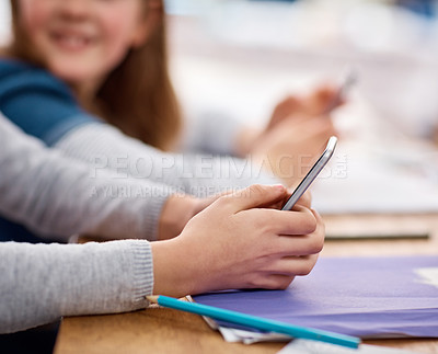 Buy stock photo Shot of an unidentifiable elementary school girl using a cellphone in class