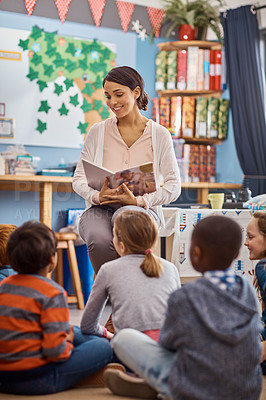 Buy stock photo Shot of a teacher reading to a group of elementary school kids in class
