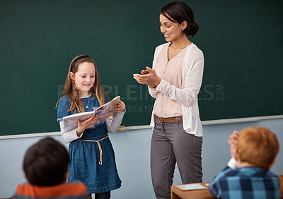 Buy stock photo Shot of a teacher applauding a young girl reading in front of the class