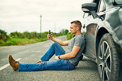Buy stock photo Shot of a young man waiting for roadside assistance after breaking down