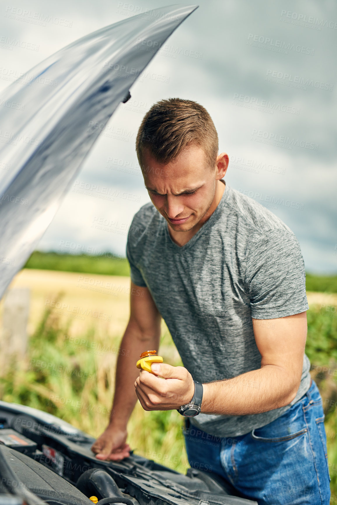 Buy stock photo Shot of a handsome young man broken down on the side of the road